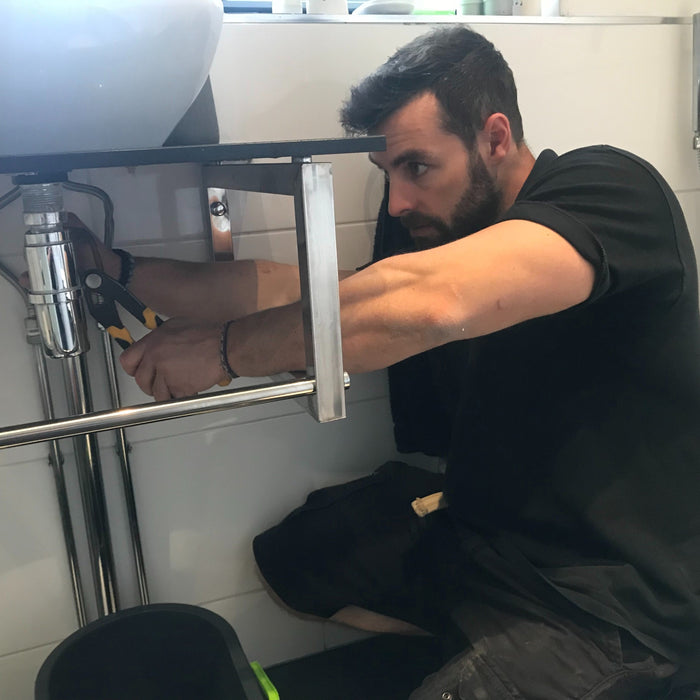 Plumber working under basin